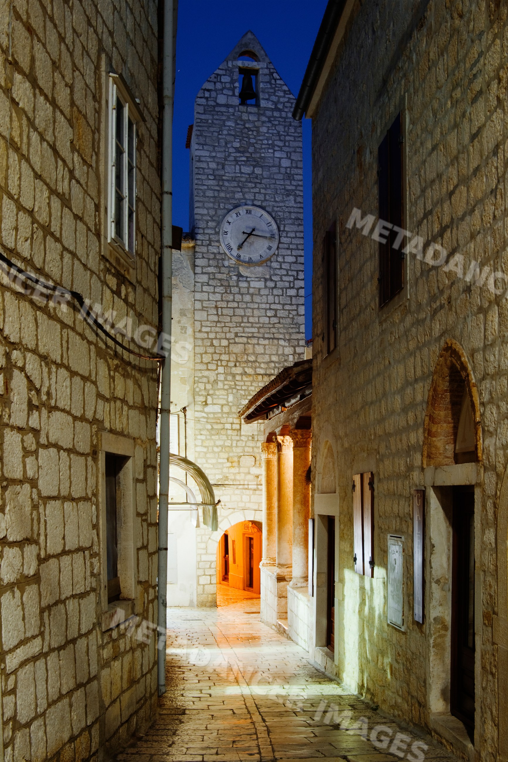 Clock tower and narrow alleyway in historic rab island, croatia