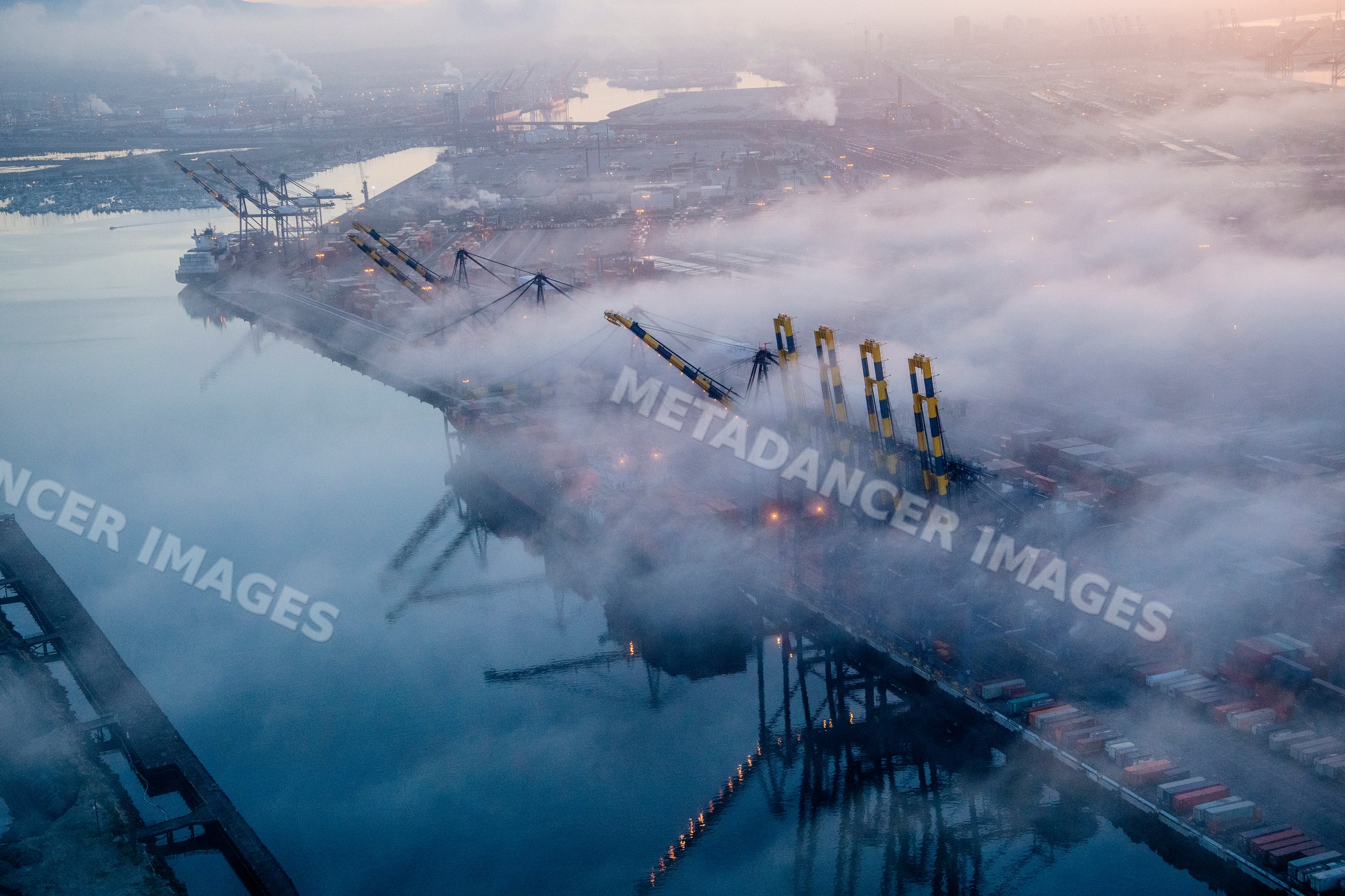 Cargo cranes and container ships in fog at a california port