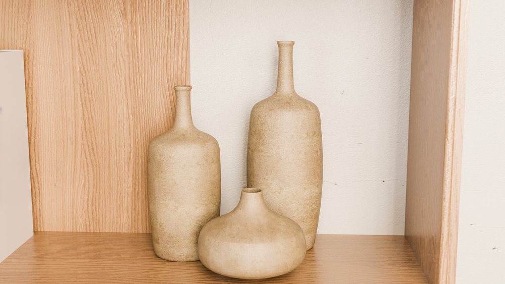 Three beige ceramic bottles on wooden shelf for minimalist interior