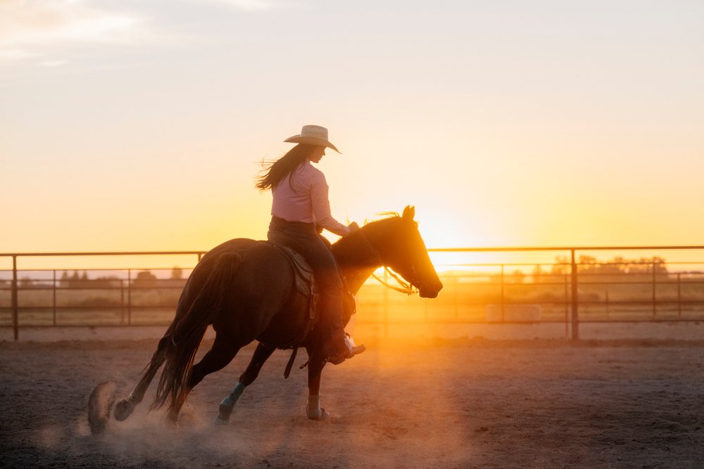 Horseback rider in dusty arena at sunset in Southwest USA