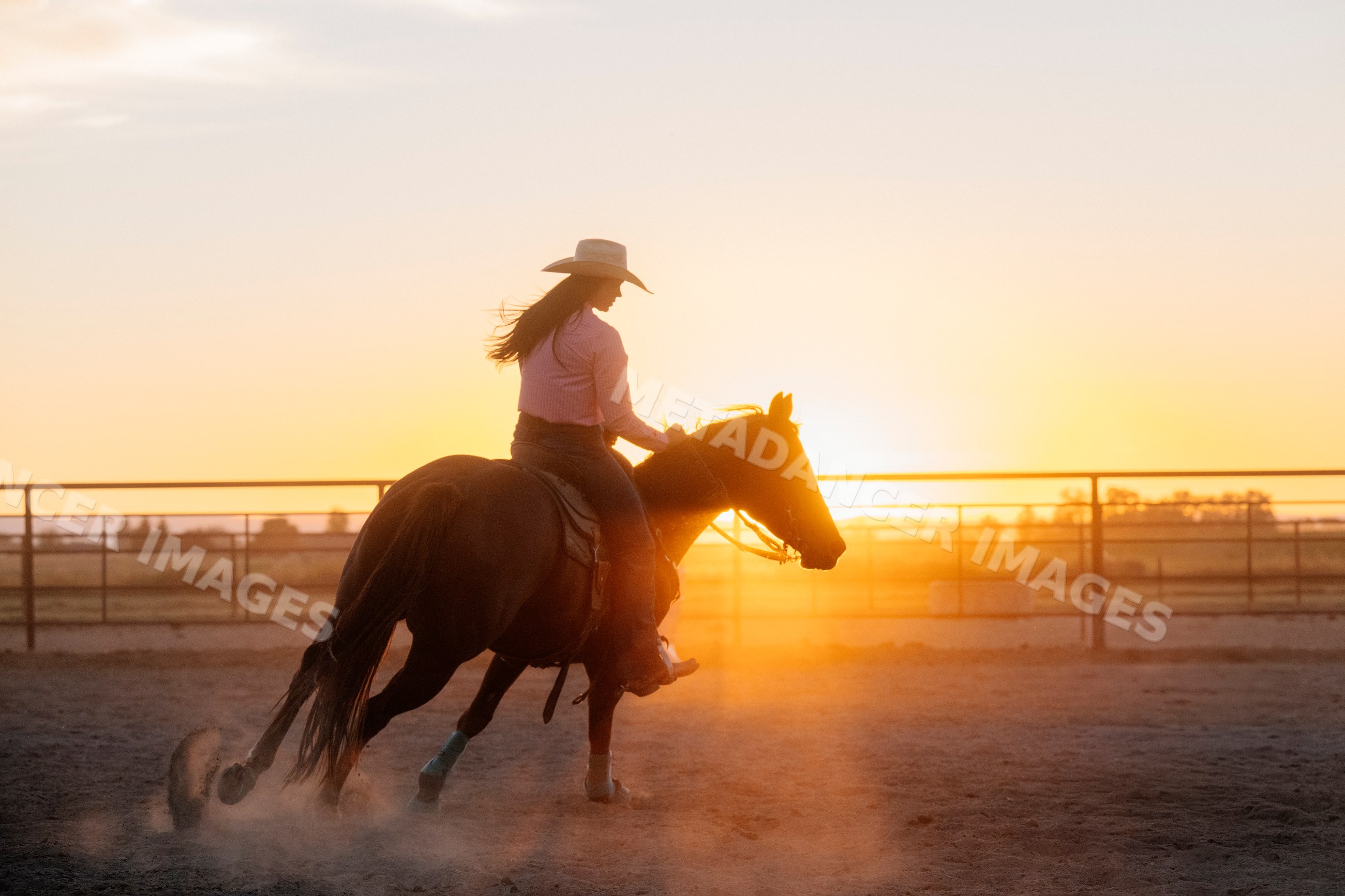 Horseback rider in dusty arena at sunset in Southwest USA