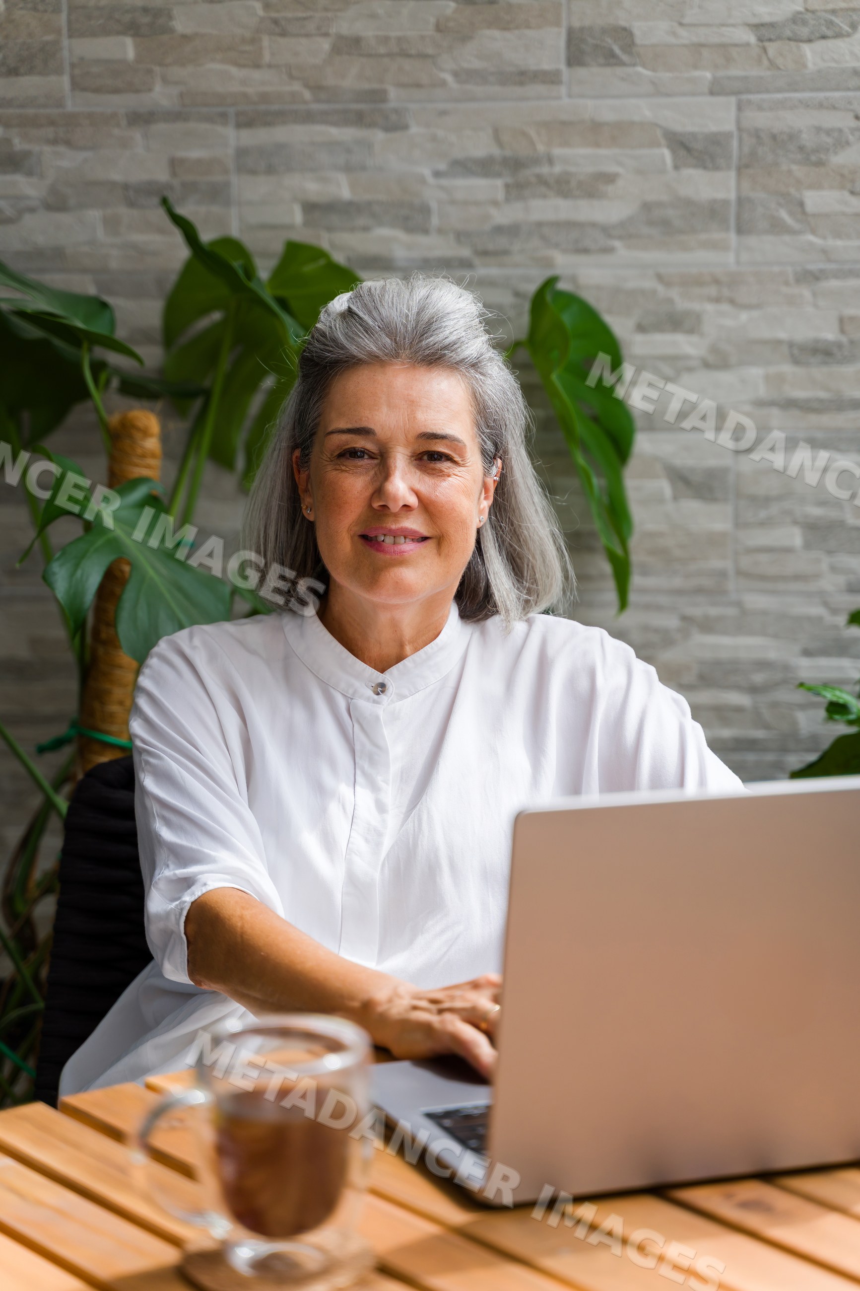White Woman working on laptop indoors at home office with coffee