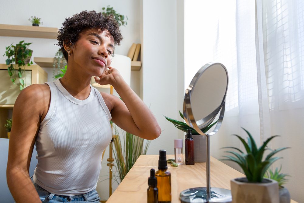 Young African American woman with skincare products looking