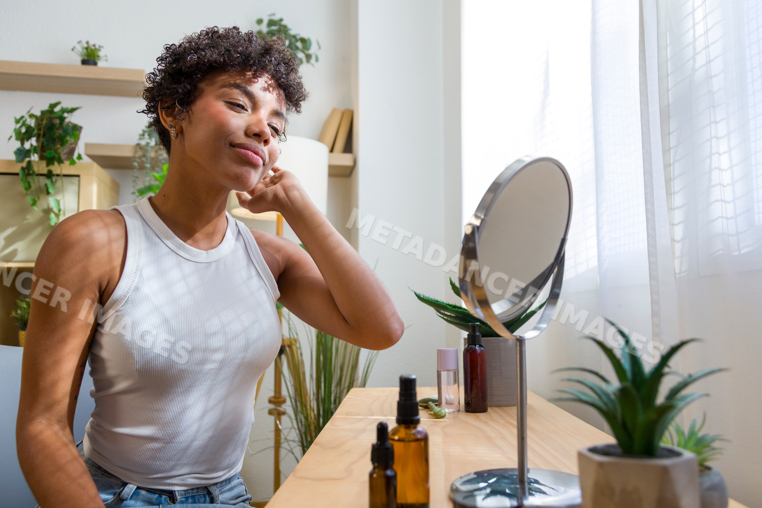 Young African American woman with skincare products looking