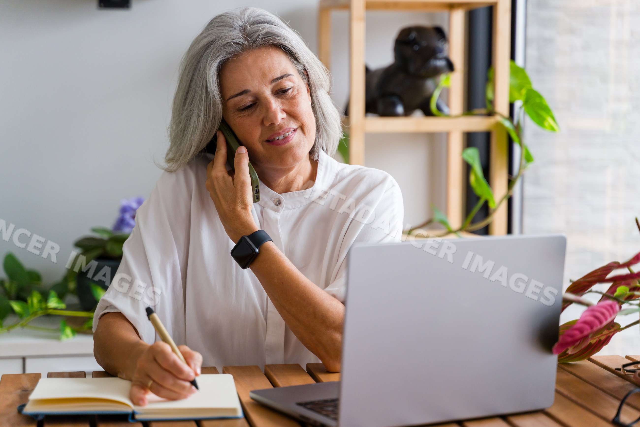 Middle-aged white woman making phone call and writing notes
