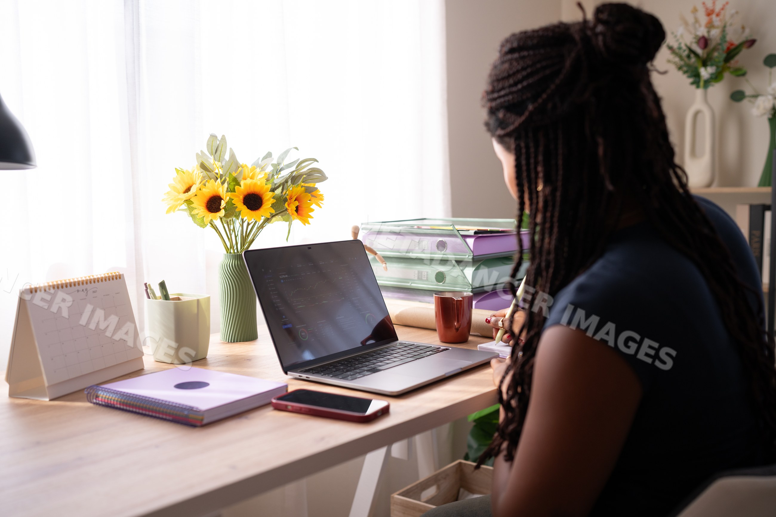 African American woman works from her home office desk with a laptop