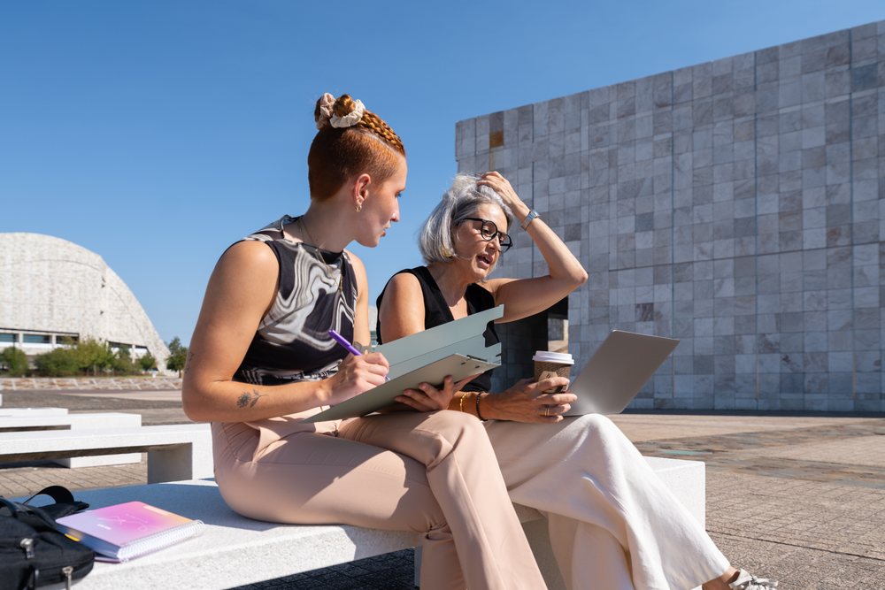 Two businesswomen collaborating outdoors in urban plaza in Spain