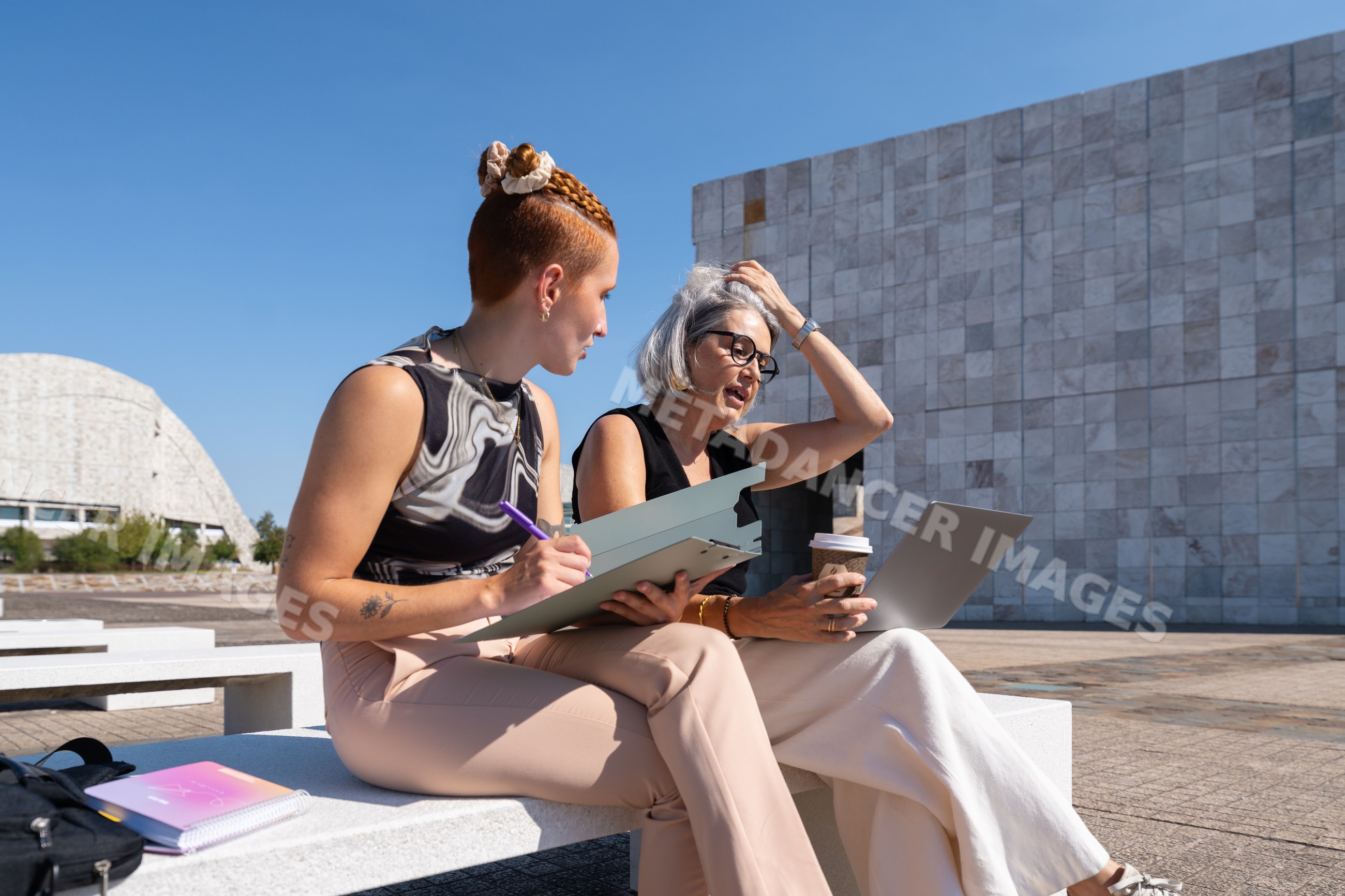 Two businesswomen collaborating outdoors in urban plaza in Spain