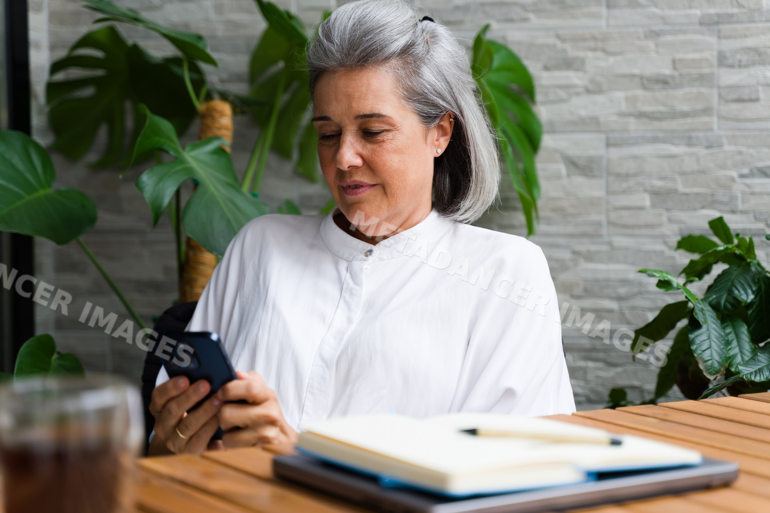 White Woman with gray hair using smartphone indoors