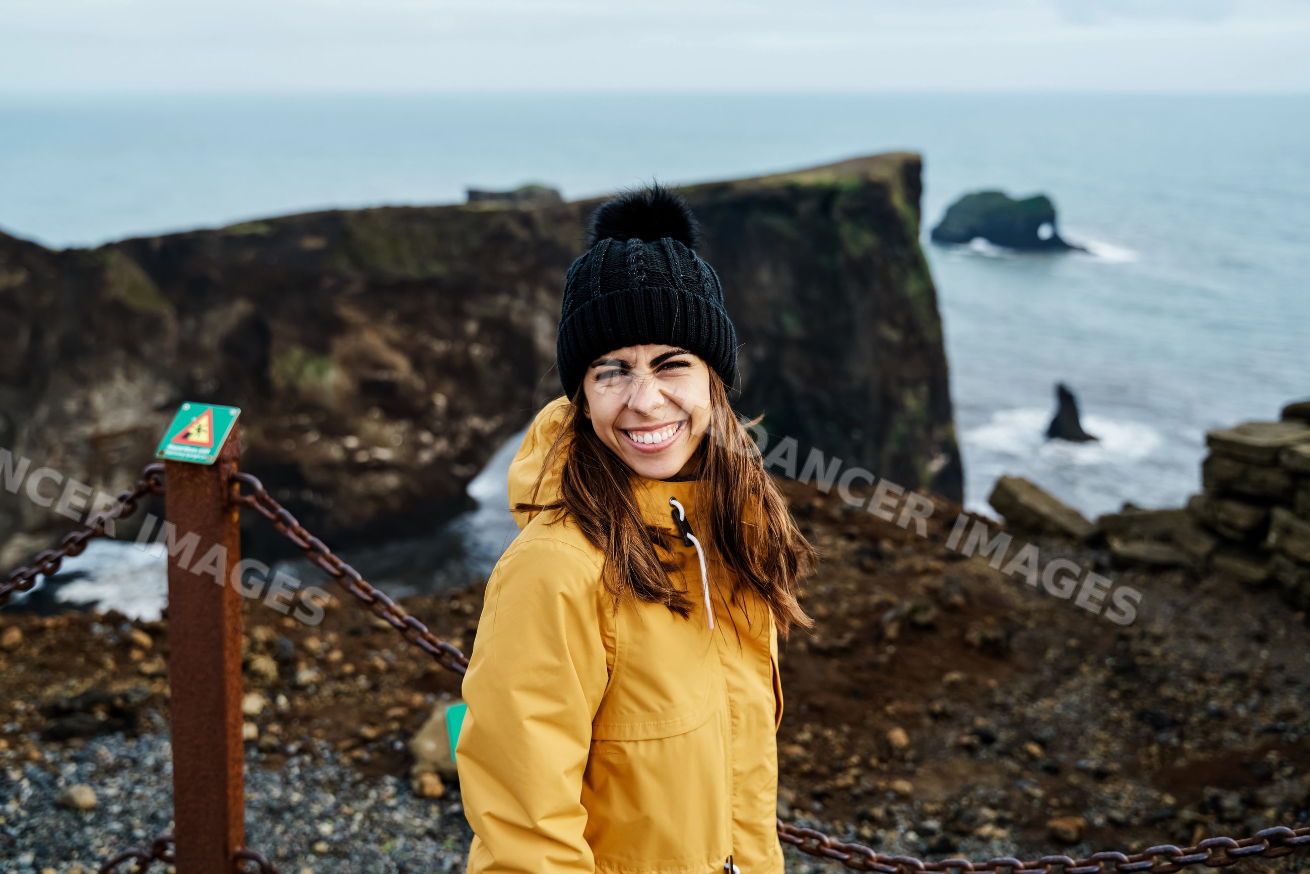 A white woman smiles on a scenic coastal cliff