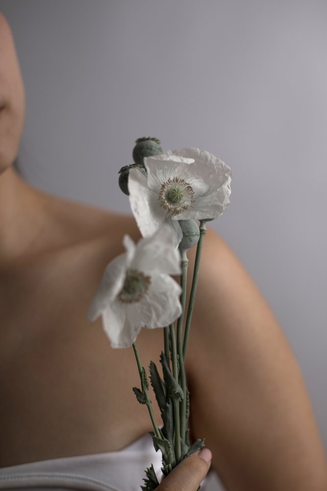 Southeast Asian woman holding delicate white poppy flowers in portrait
