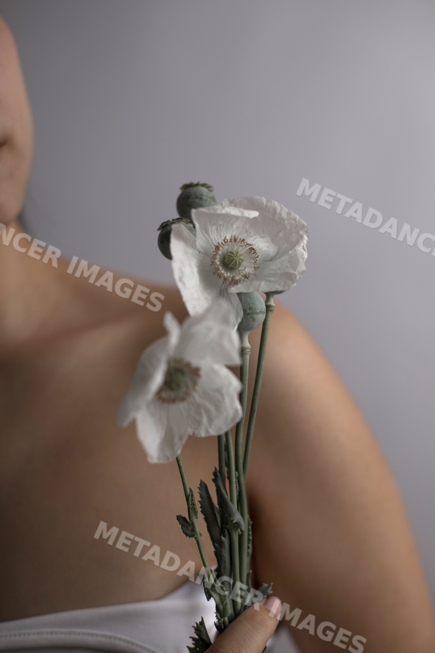 Southeast Asian woman holding delicate white poppy flowers in portrait