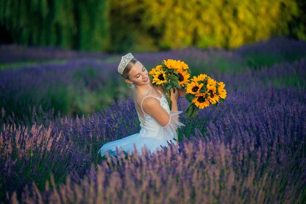 Young white woman wearing crown holds sunflower bouquets