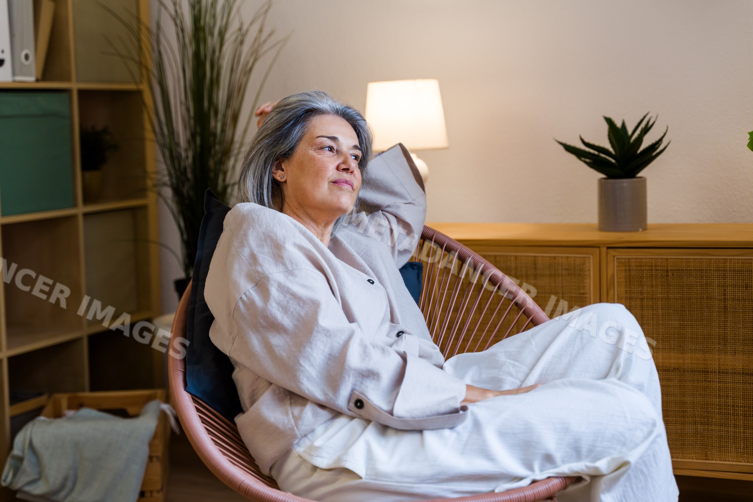 White woman relaxing thoughtfully in modern living room armchair
