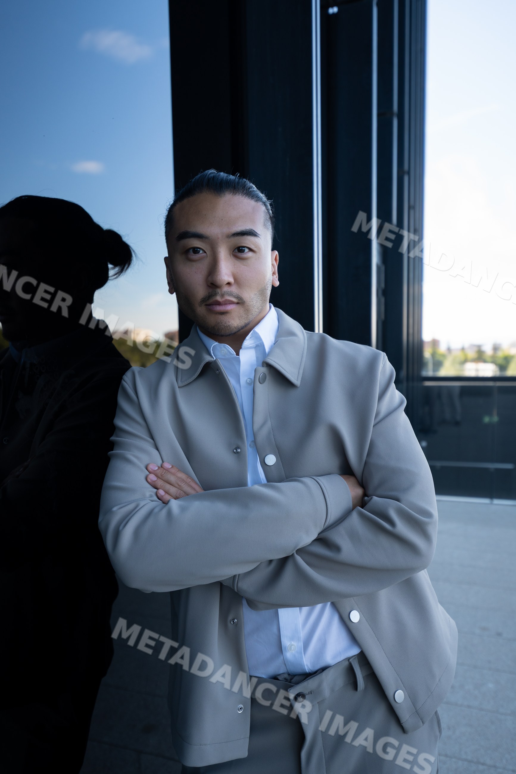 Man with crossed arms leaning against glass wall