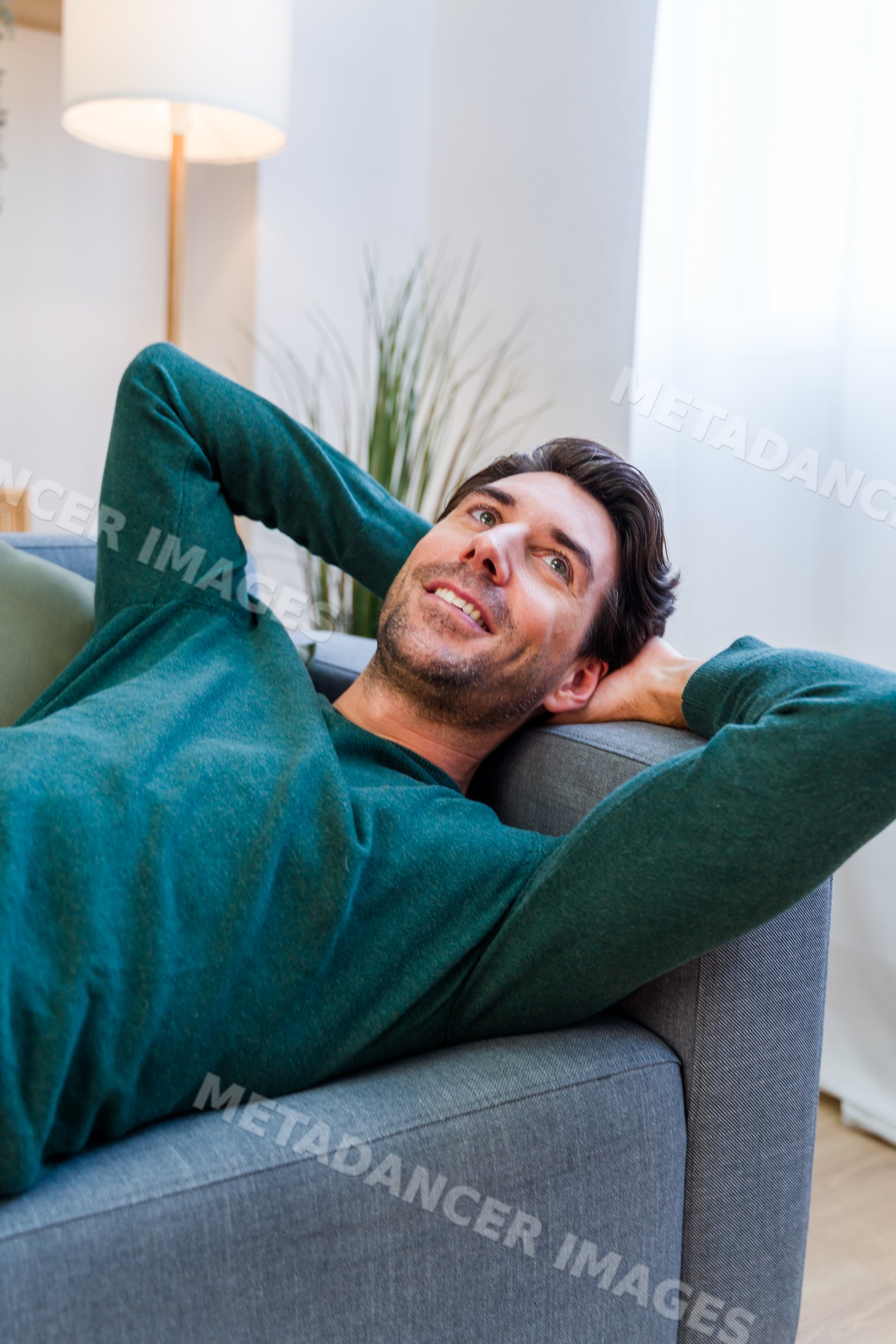White man relaxing on sofa at home in casual sweater