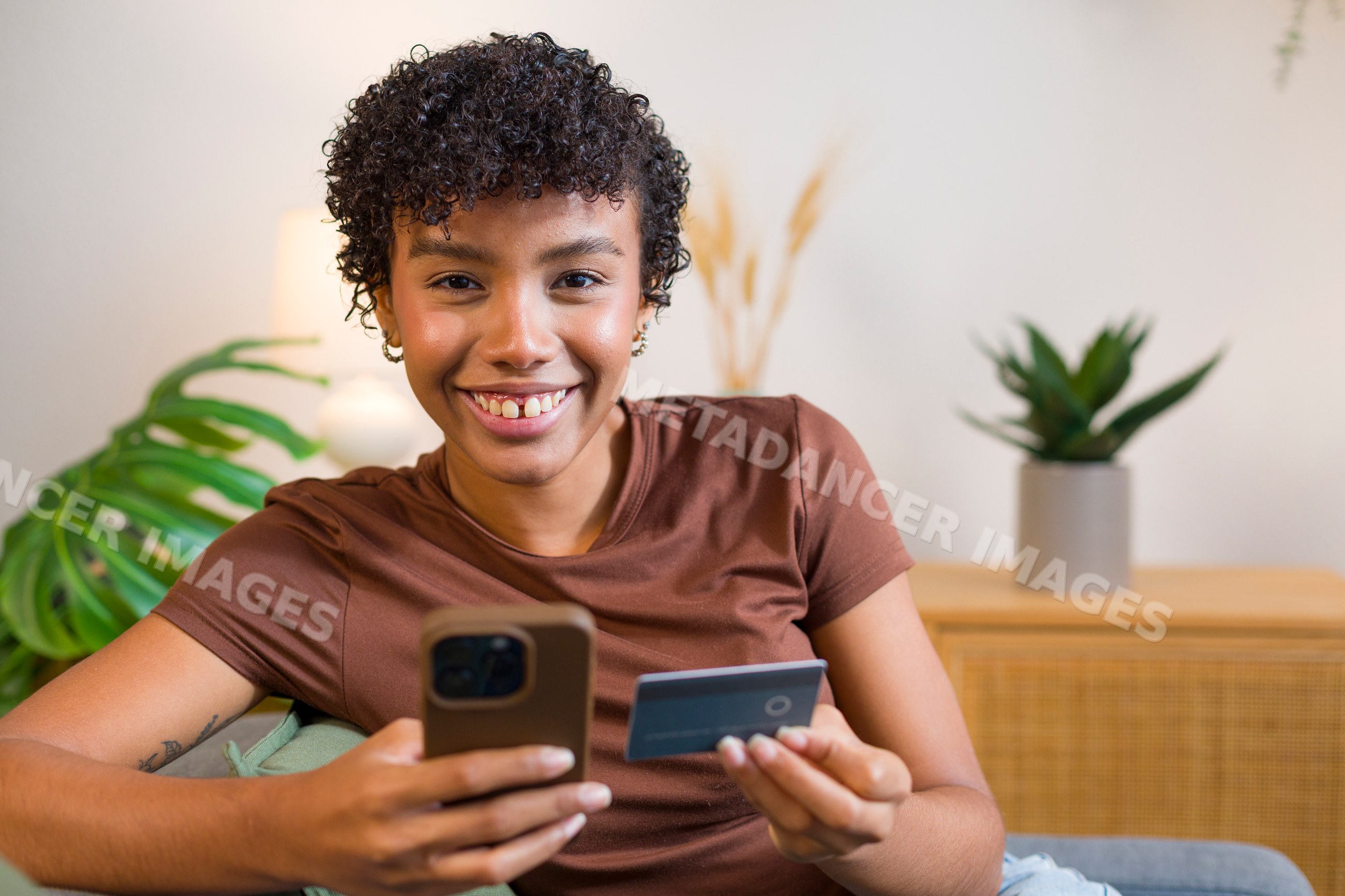 Young African American woman using smartphone and credit card at home