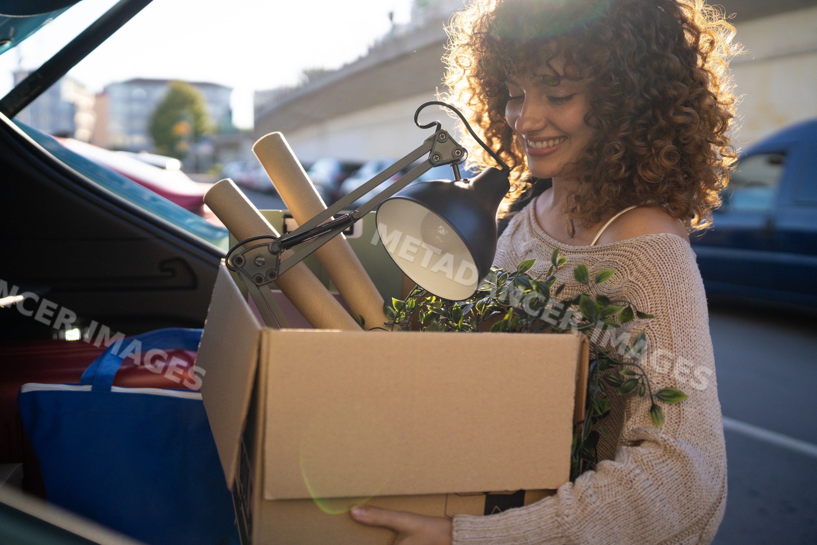White woman carrying a cardboard box with household items