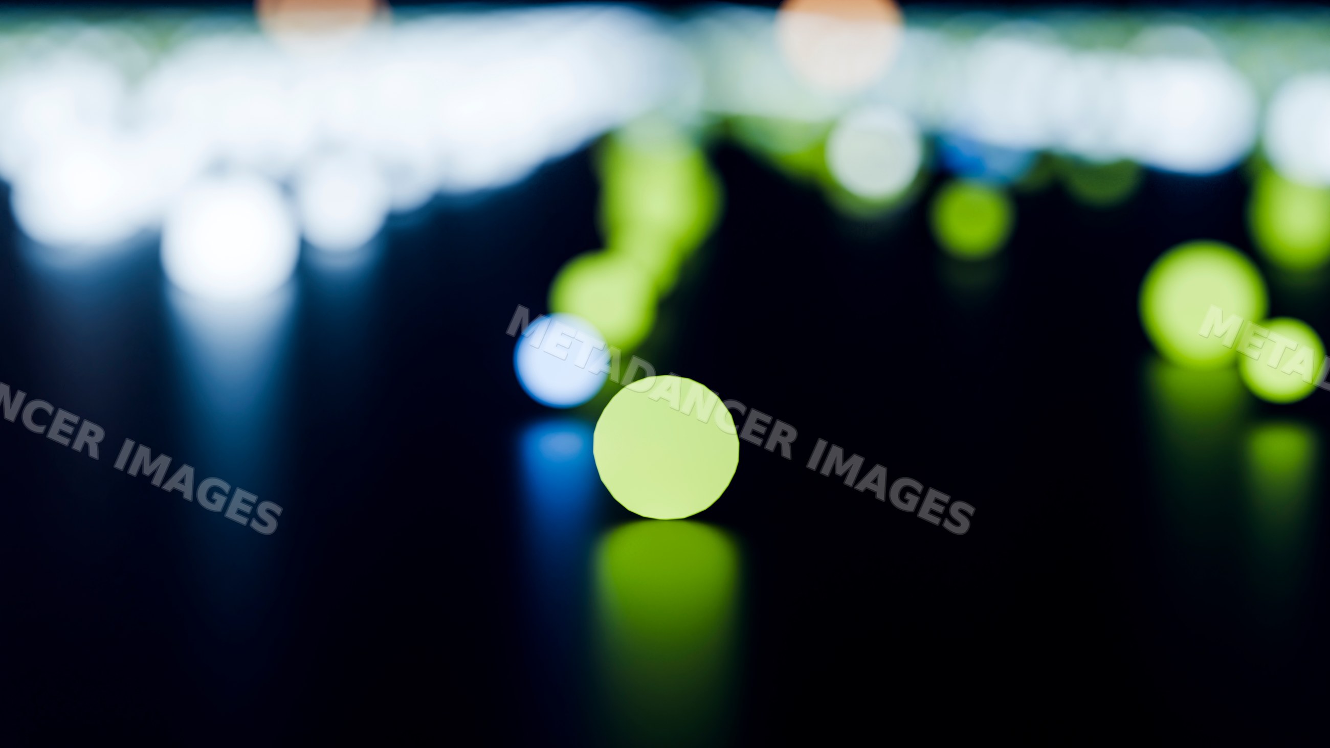 Colorful round bokeh lights glowing on dark reflective surface