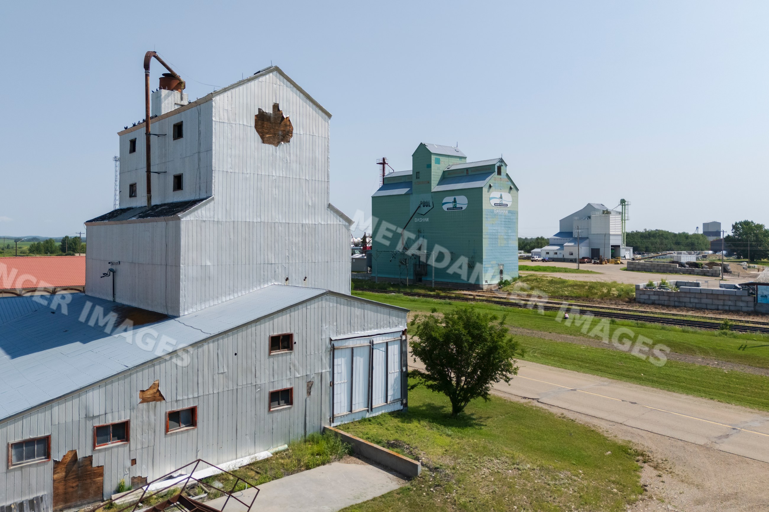 Grain elevator and industrial buildings beside railroad tracks