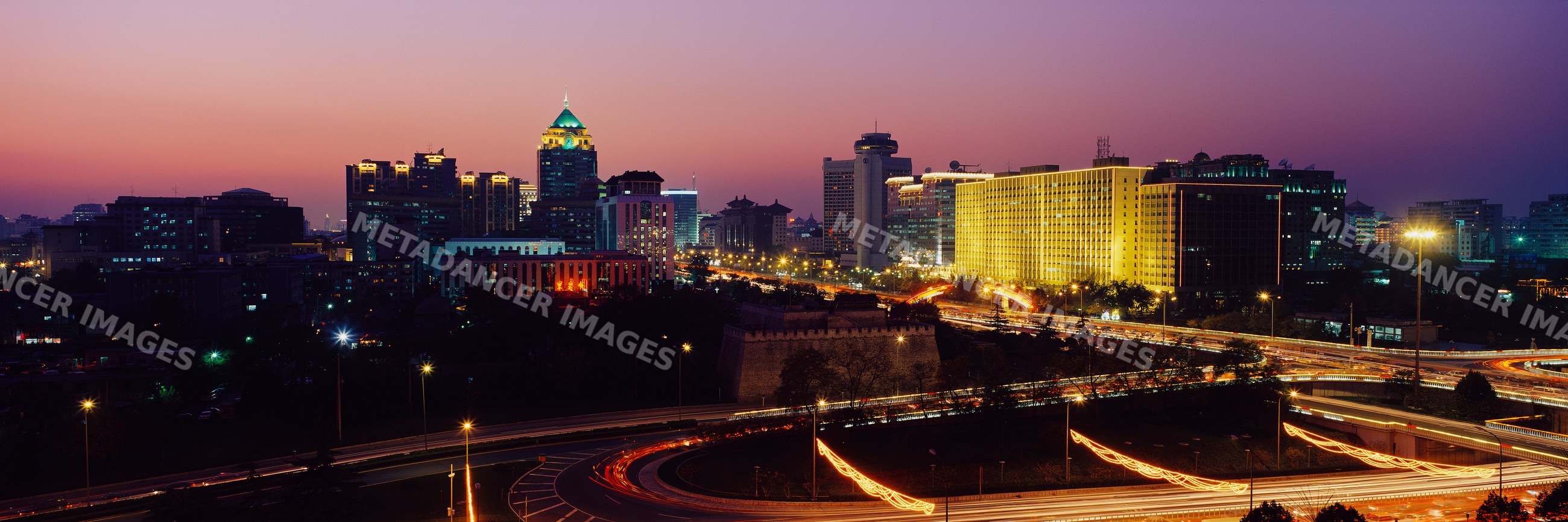 City skyline with traffic and illuminated buildings at sunset