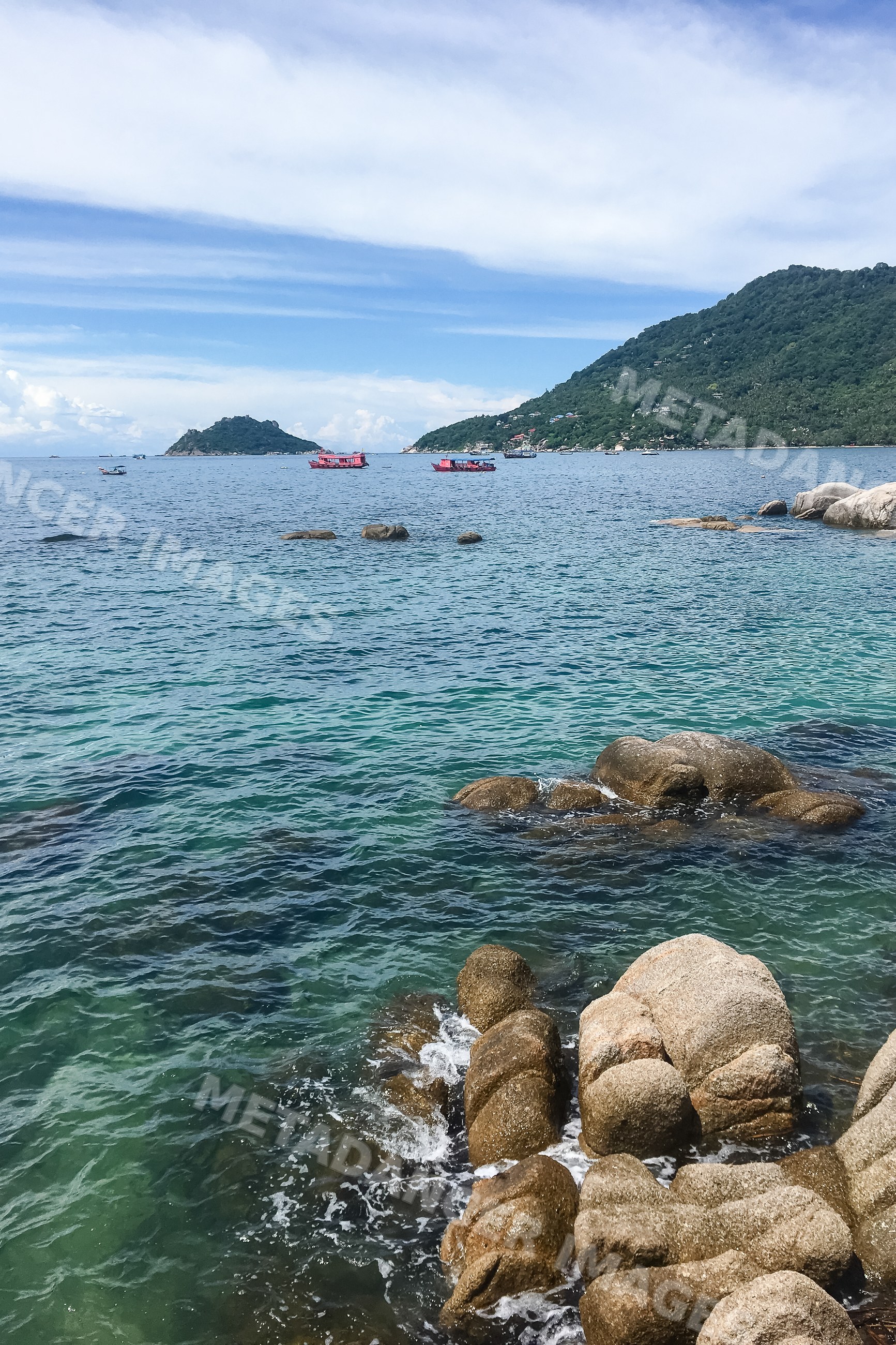 Rocky coast with boats and islands under blue sky