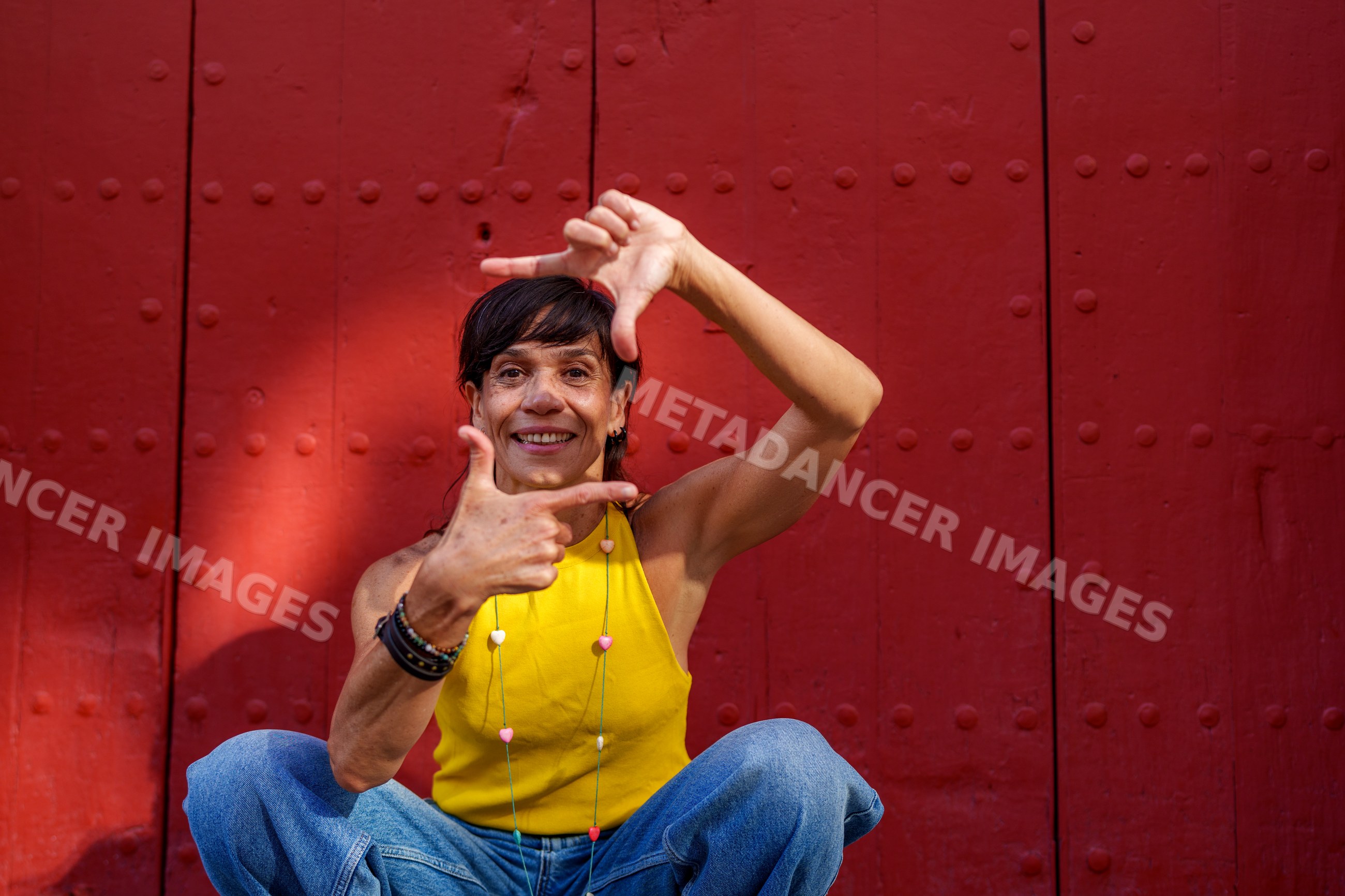 Hispanic woman framing face with hands against red door