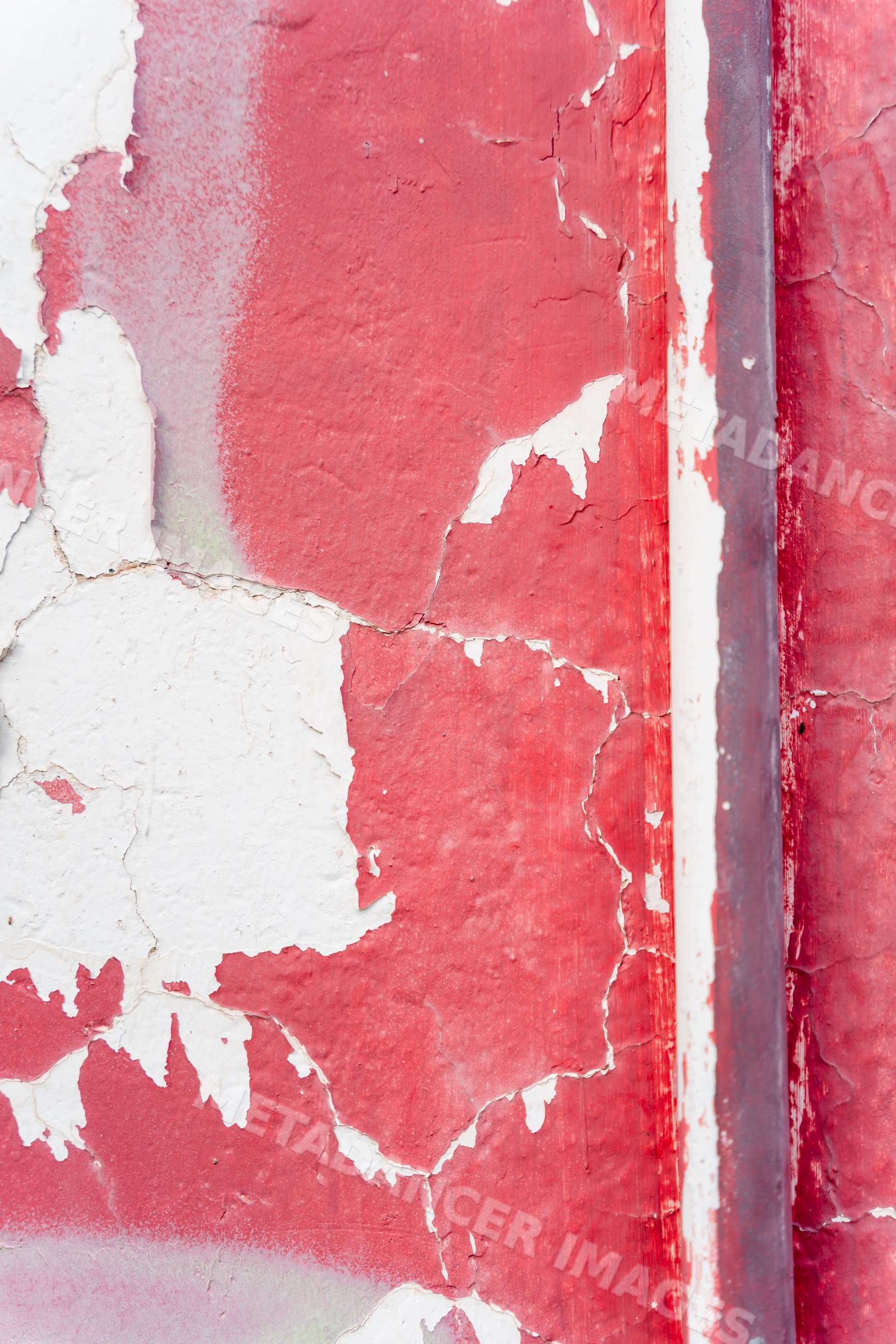 Peeling and cracked red and white paint texture on weathered wall