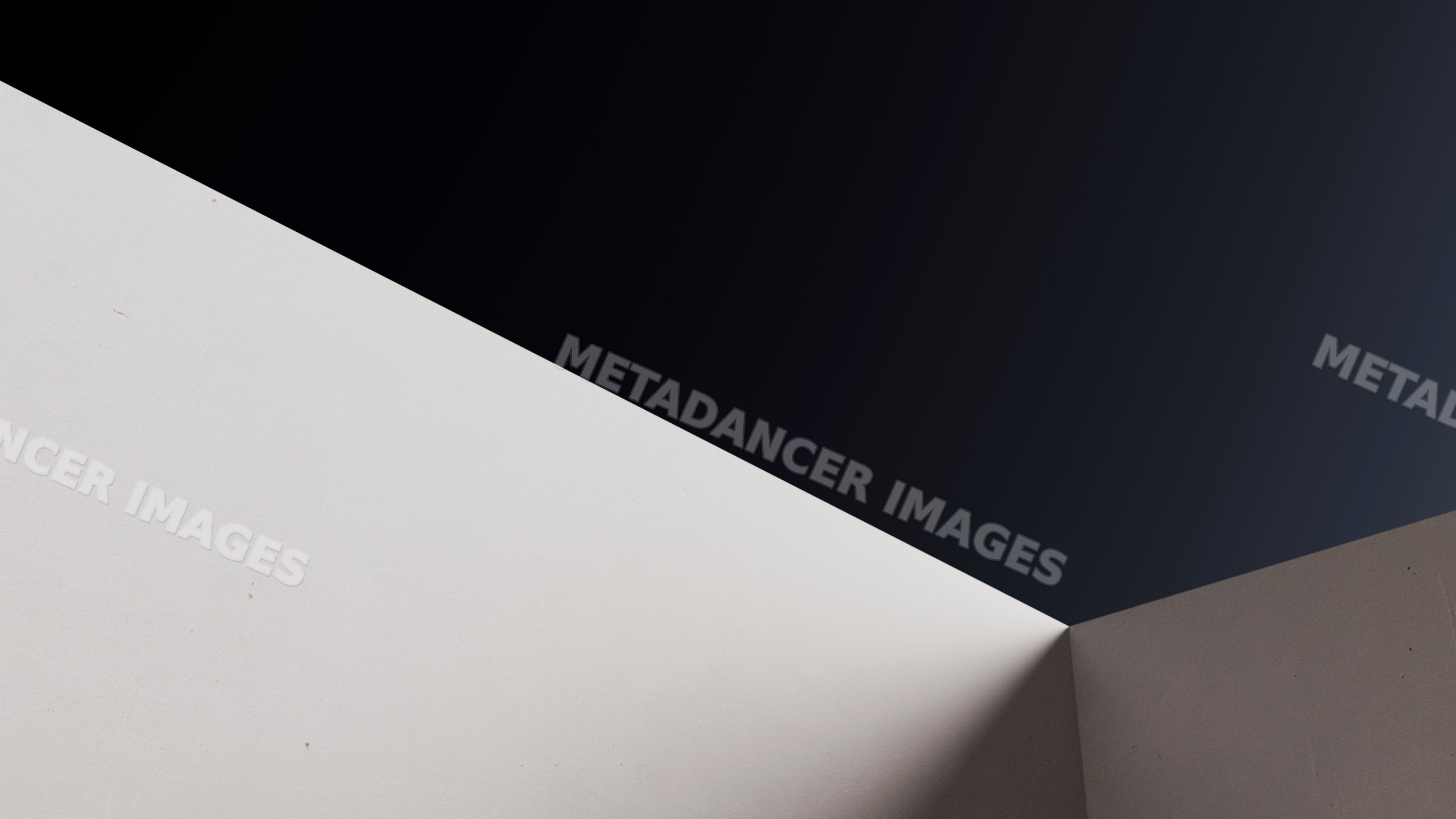 Corner of white and gray walls with shadow and dark background