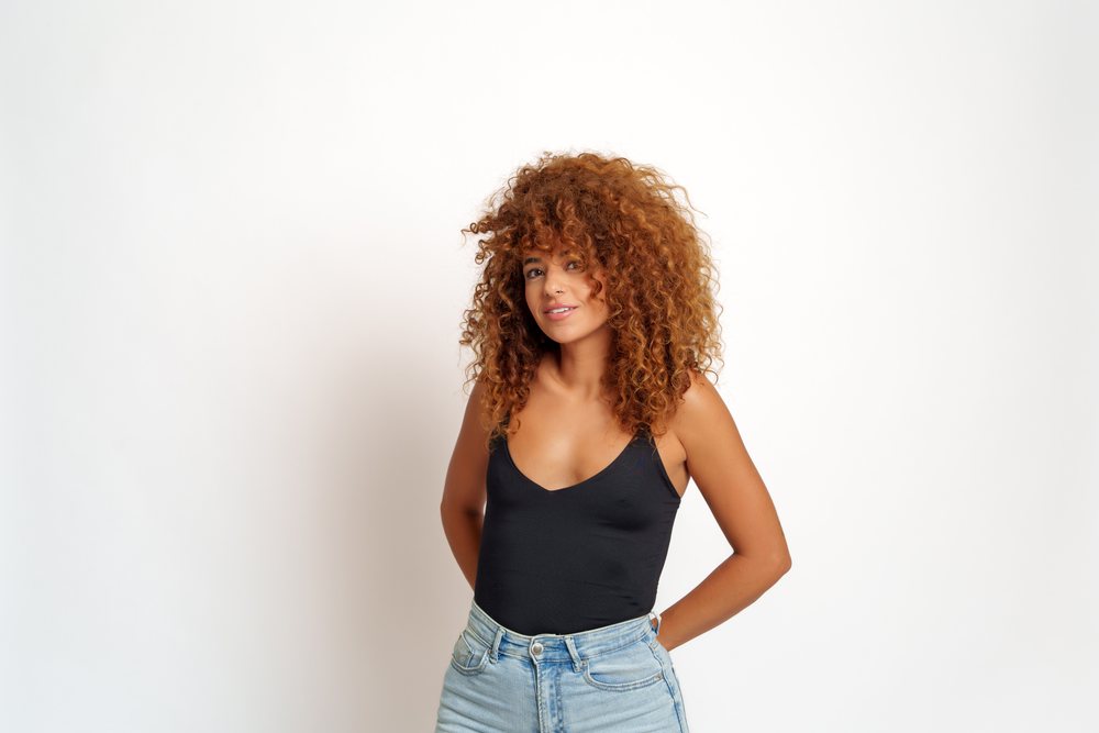 Hispanic woman with curly red hair posing