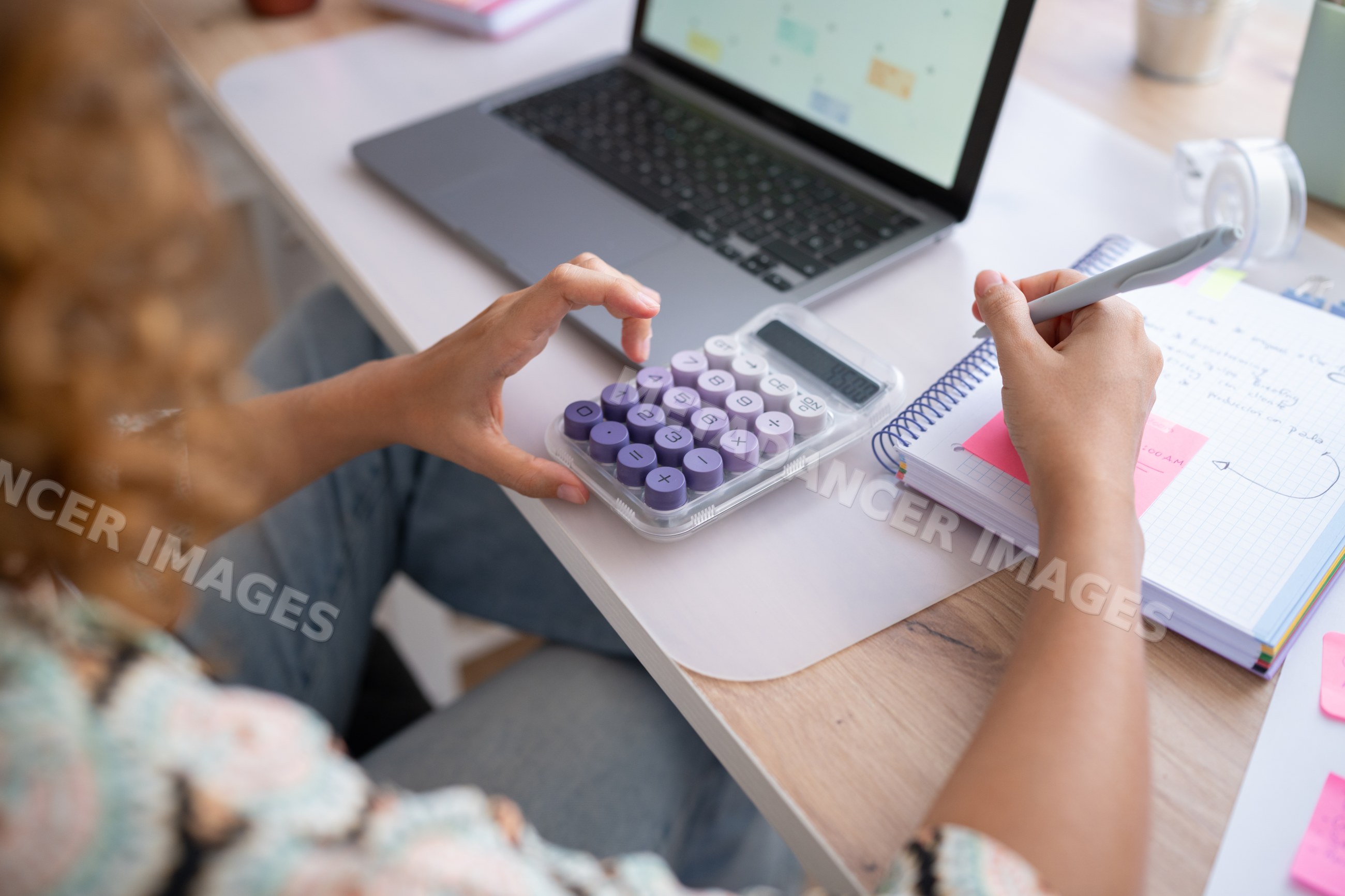 White woman using calculator and writing notes