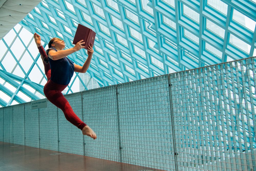 A dancer leaps holding a book