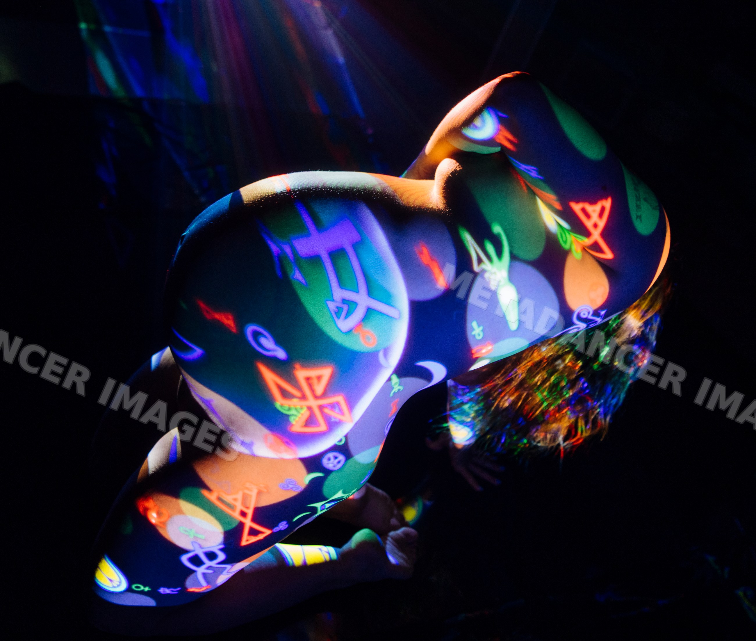 Pregnant white woman with colorful projection body art kneeling