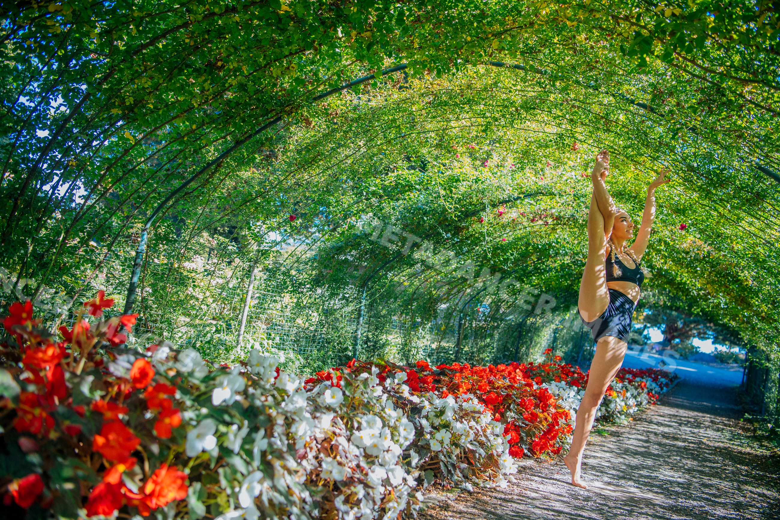 Contortionist stretching in garden tunnel with flowers