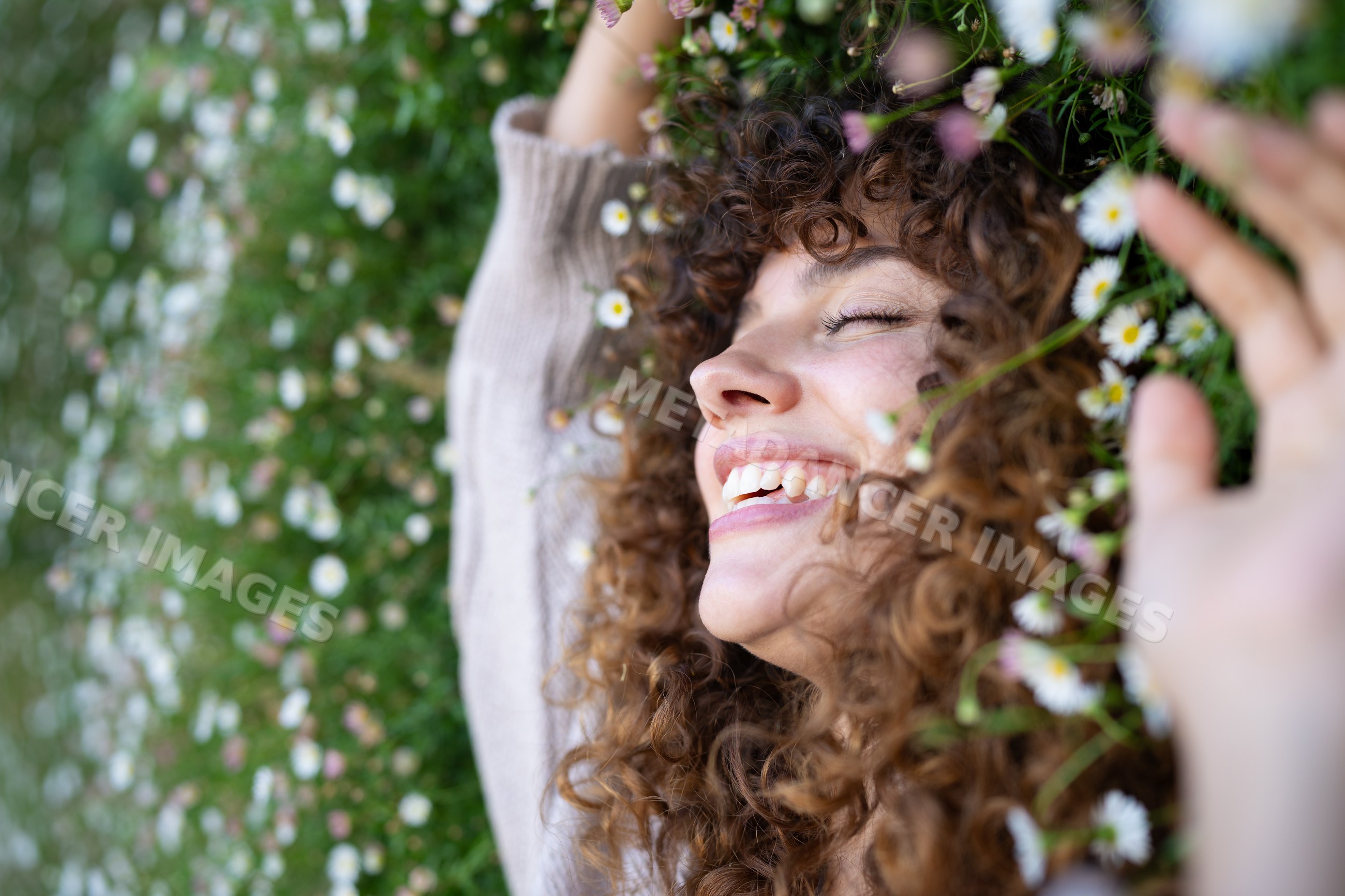 White woman with curly hair smiling and lying