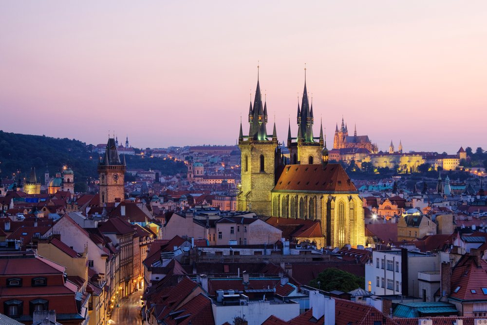 Tyn church towers over prague rooftops at sunset