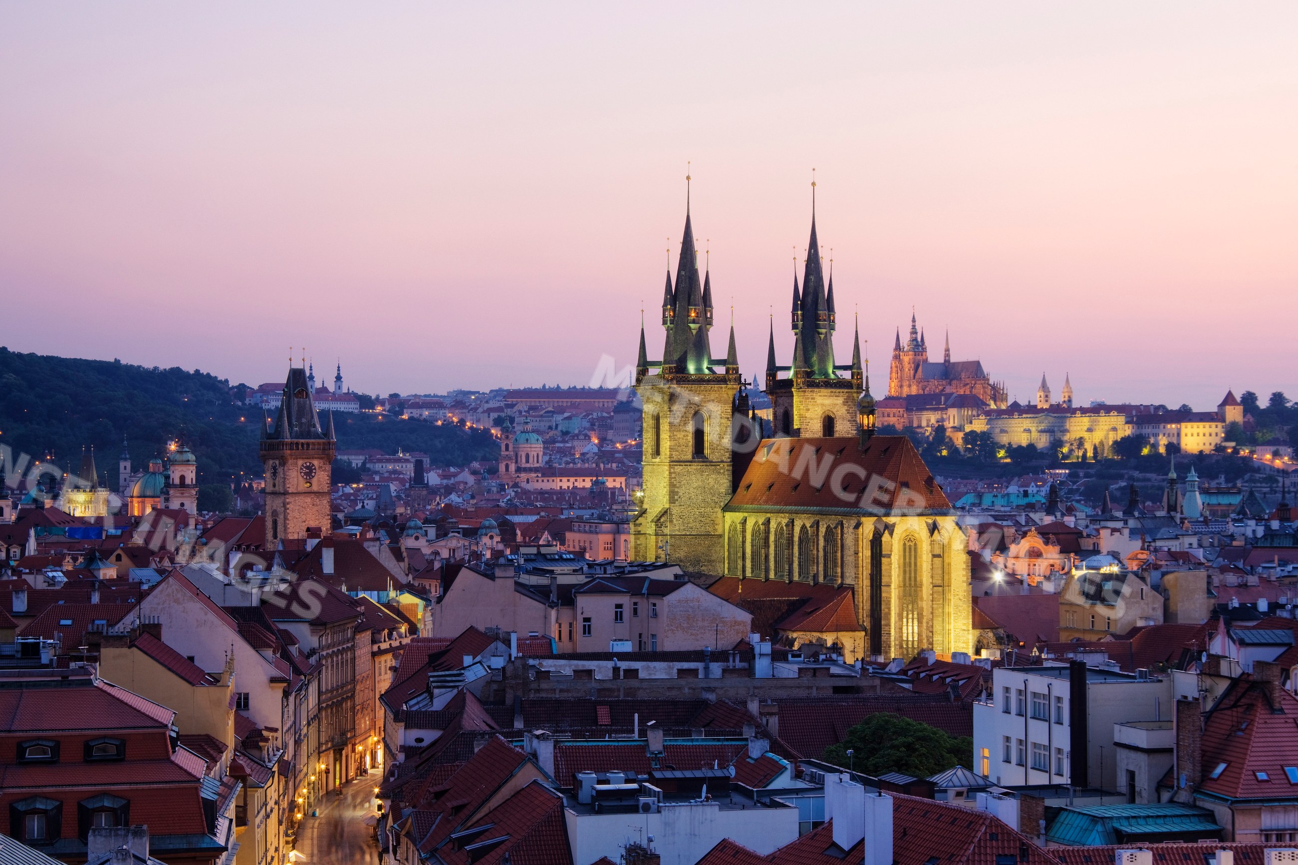 Tyn church towers over prague rooftops at sunset