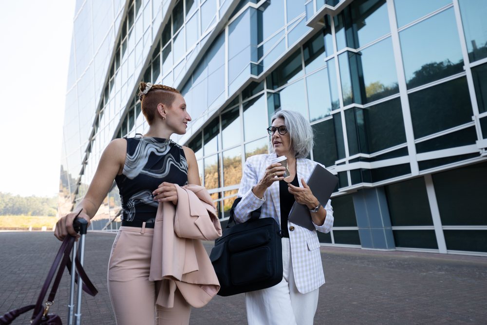 Businesswomen walking and talking outside modern office building