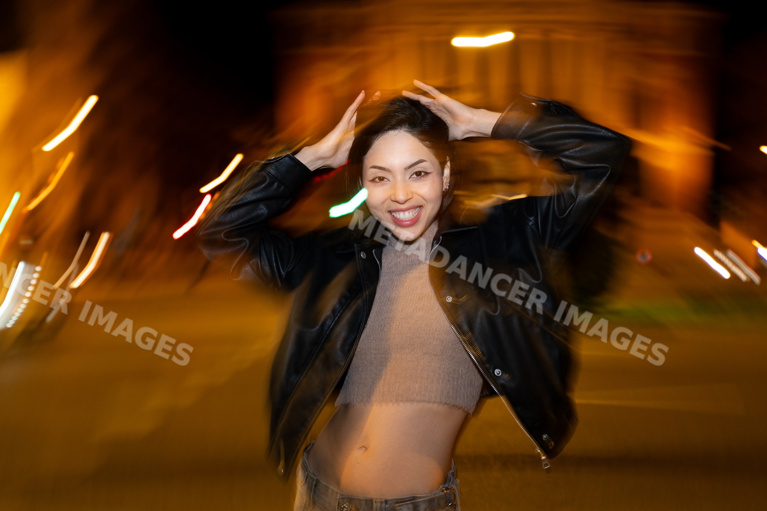 Hispanic woman smiling and posing at night on urban street in a street
