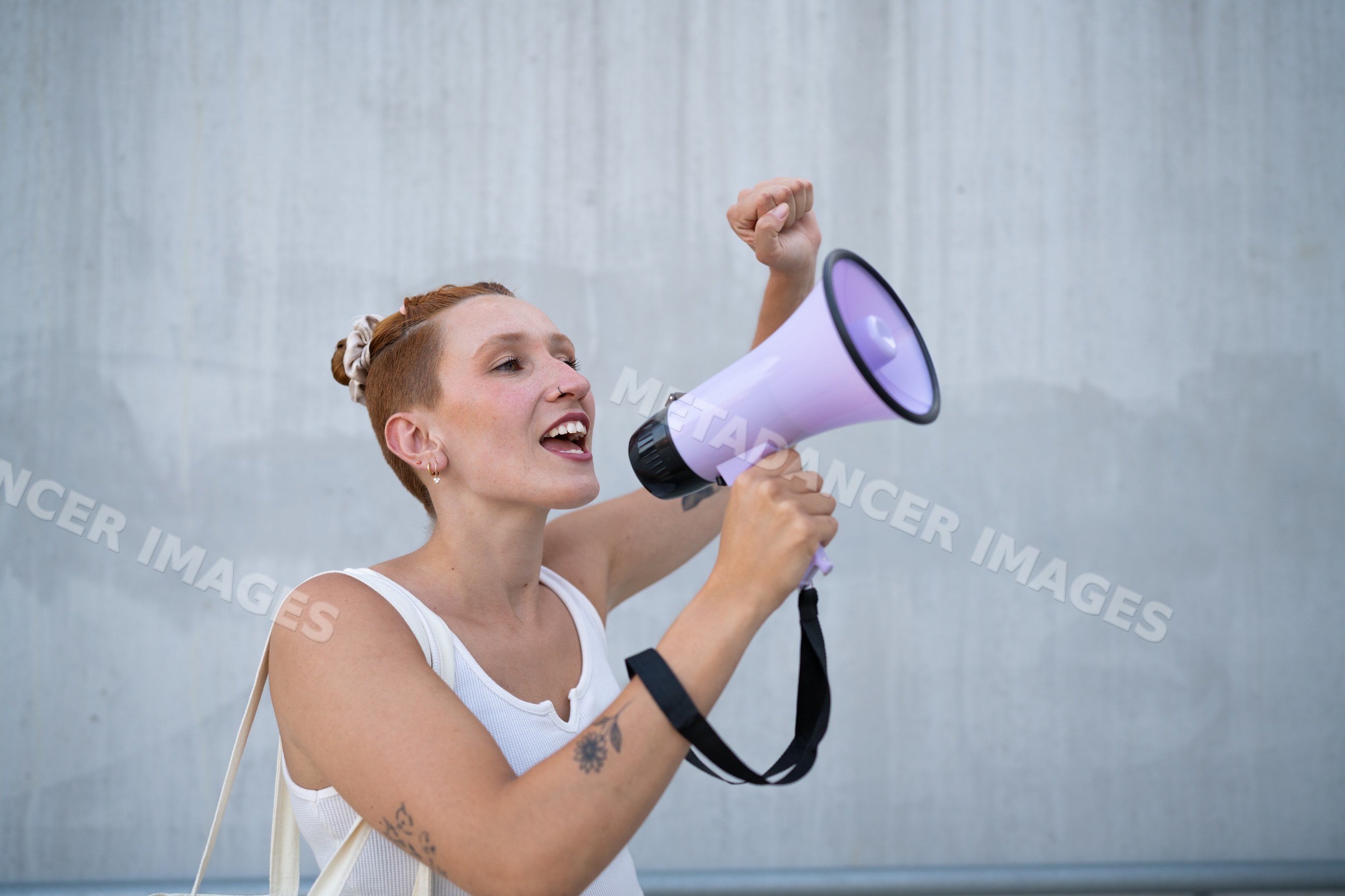 A white woman speaks passionately into a megaphone in an urban setting
