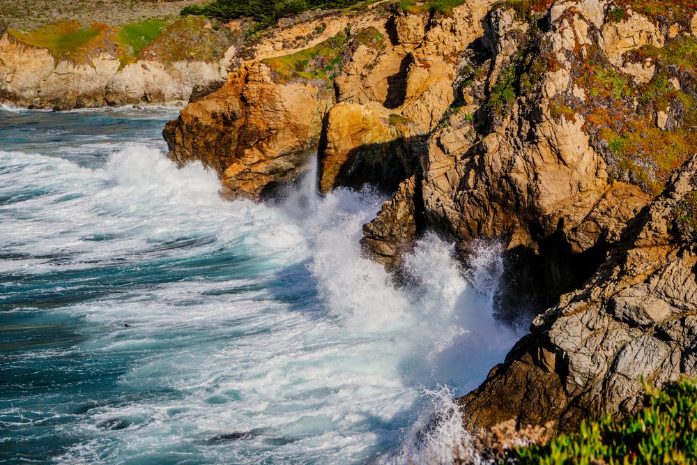 Waves crashing on rocky cliffs along the California coastline