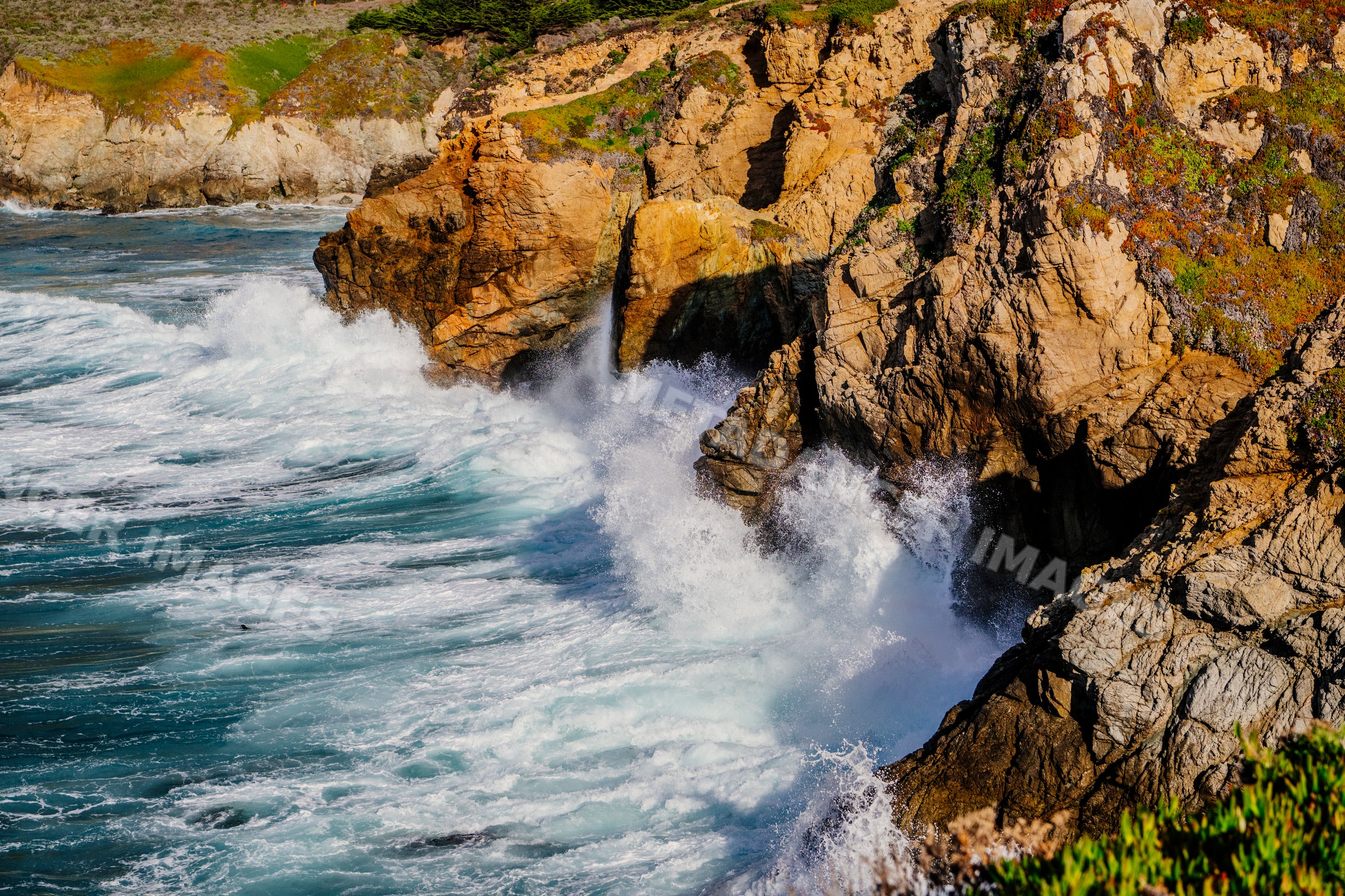 Waves crashing on rocky cliffs along the California coastline
