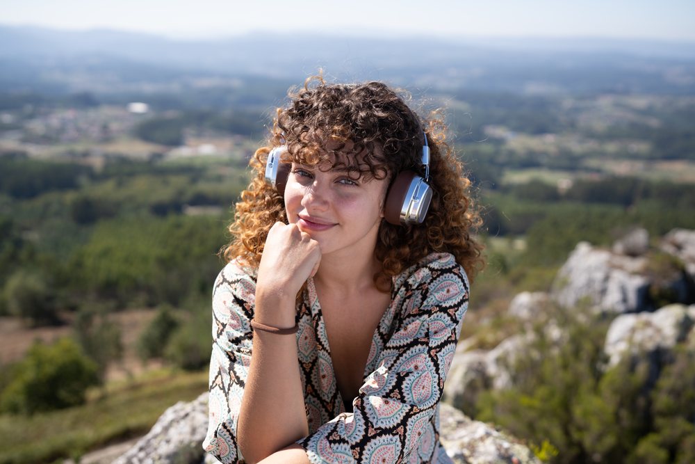 Young white woman enjoying scenic outdoor view with headphones