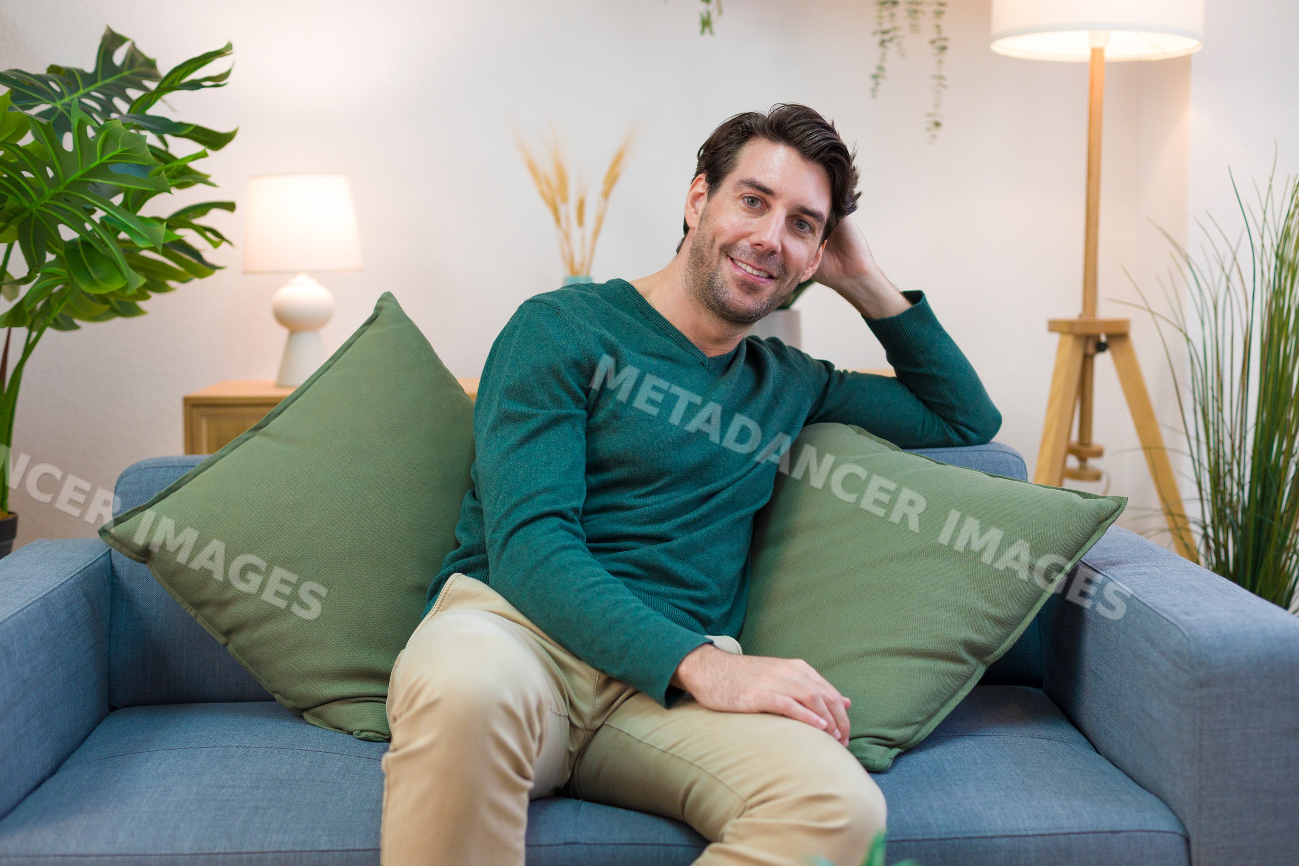White man relaxing on sofa in modern living room at home