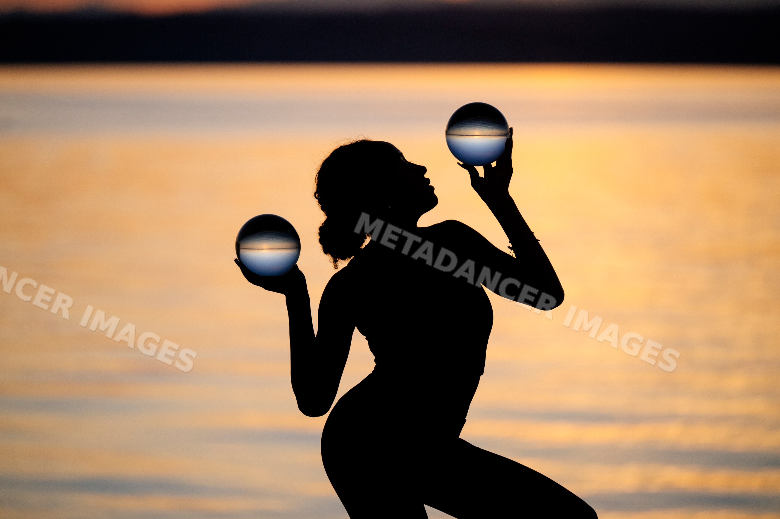 Silhouette of Hispanic woman balancing crystal balls