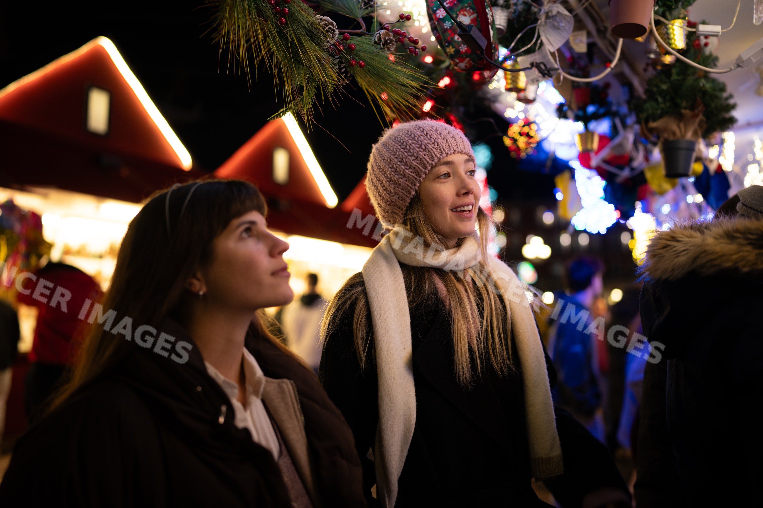 White women shopping amid festive christmas market illuminating Madrid