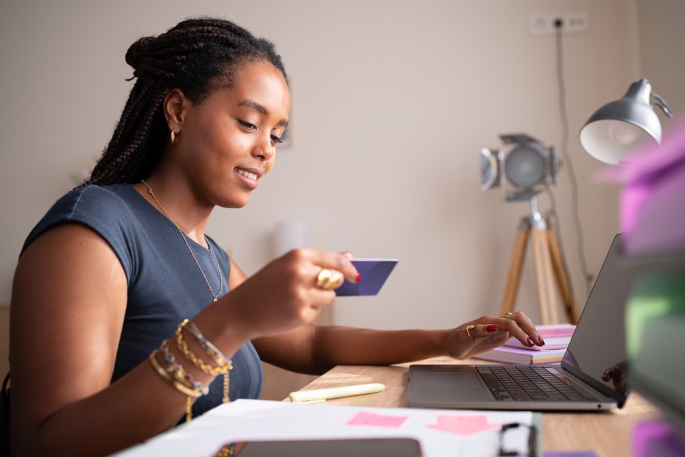 African American Woman uses a credit card and laptop