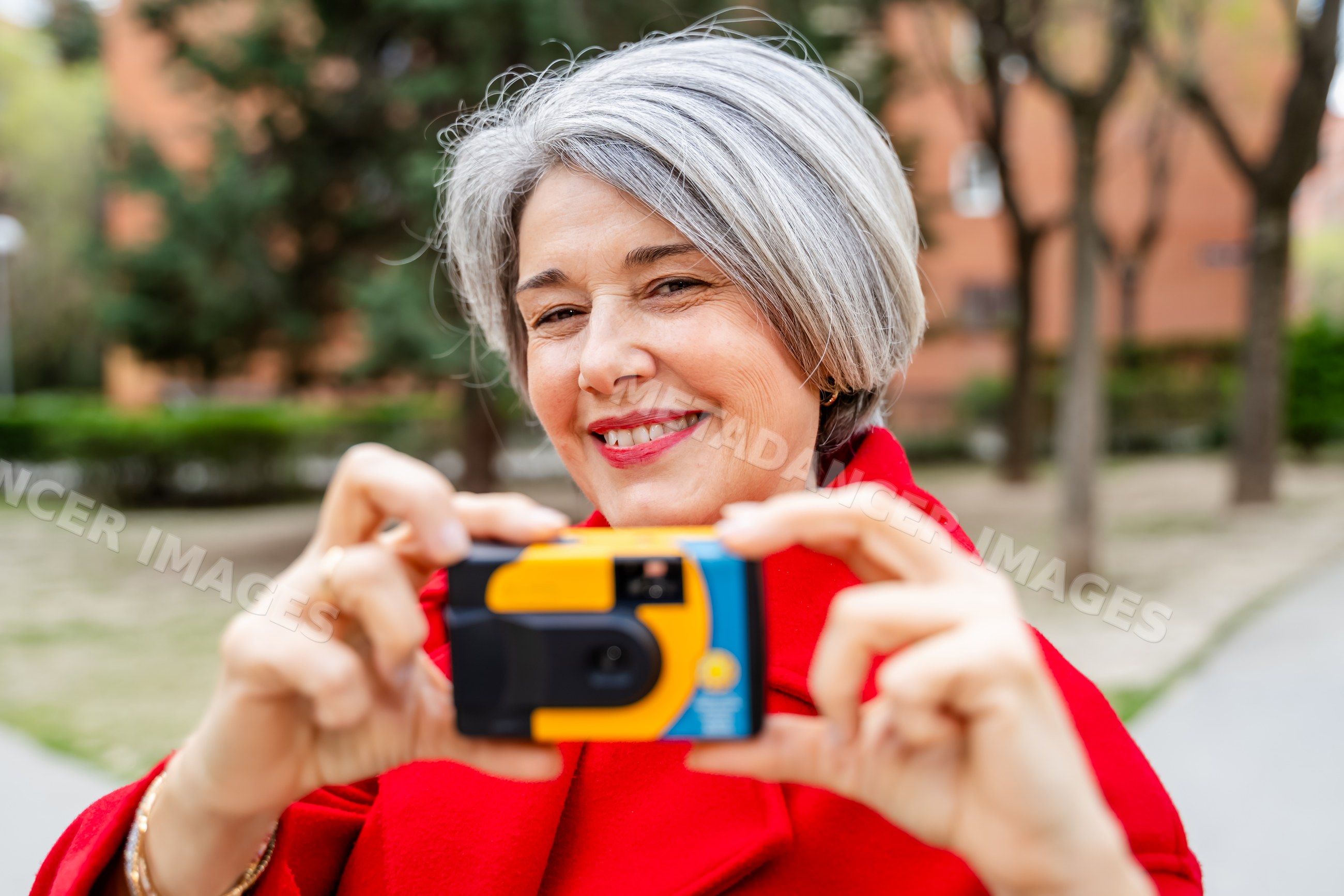White woman smiling and taking photo with disposable camera outdoors