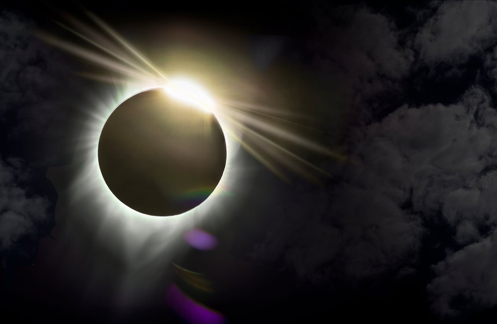 Solar eclipse with glowing sun corona behind the moon in dark sky