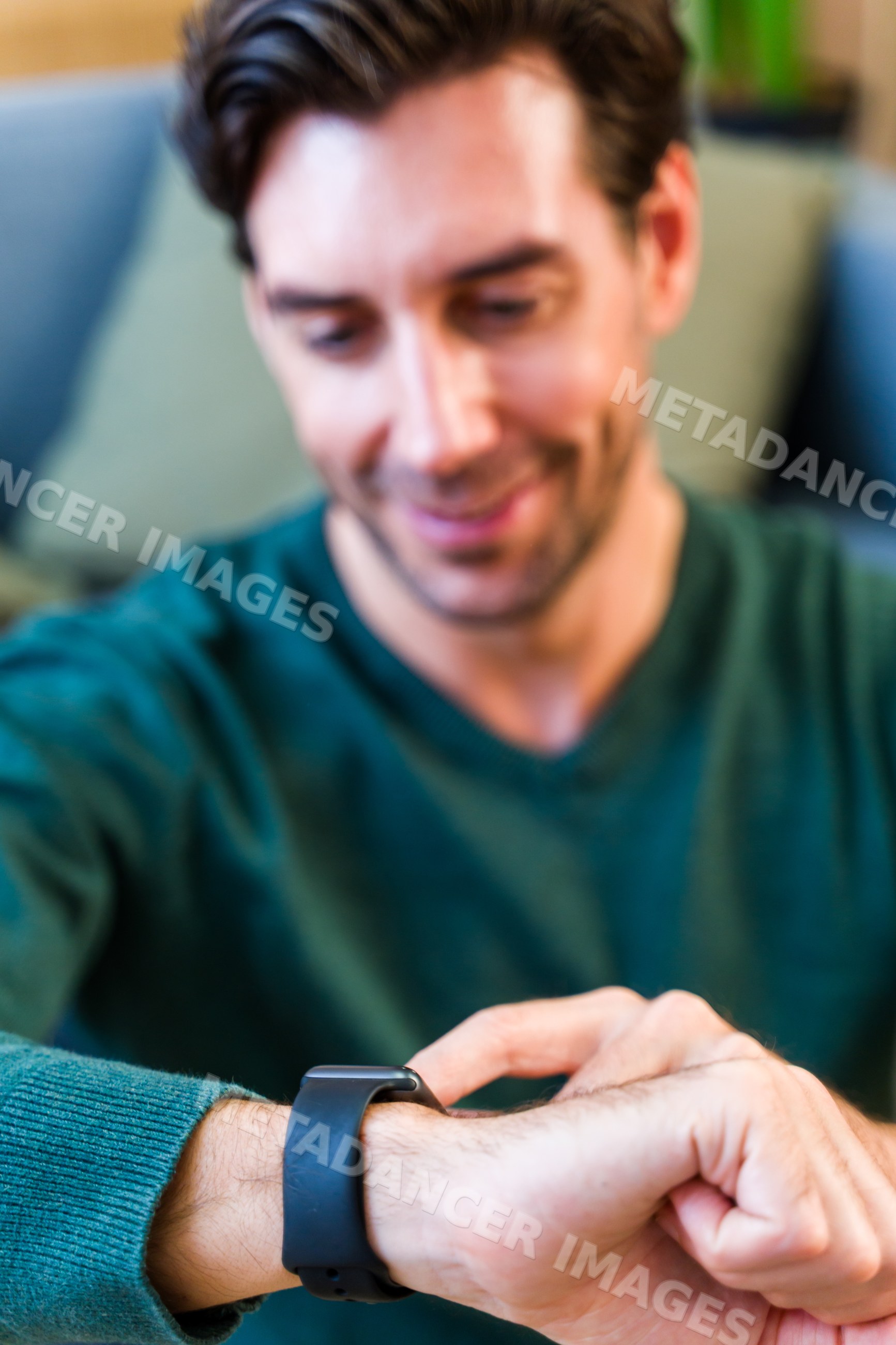 White man using black smartwatch indoors in casual setting